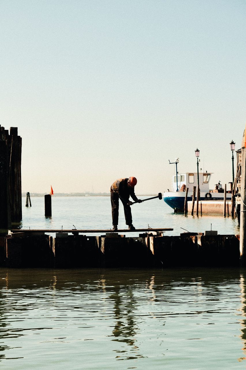 Worker repairing a dock beside the water